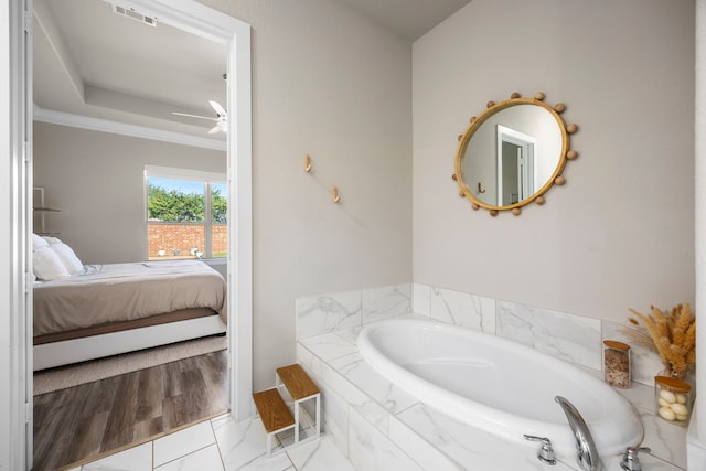 bathroom featuring tiled bath, tile patterned flooring, and ornamental molding