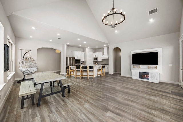 dining space featuring hardwood / wood-style flooring, high vaulted ceiling, and an inviting chandelier