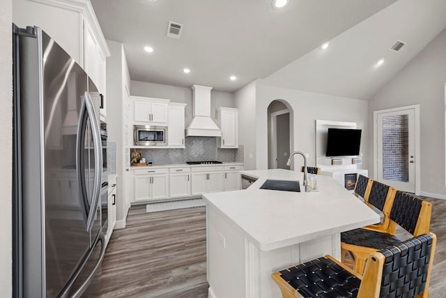 2215 Rose Manor Ct, Richmond, TX 77469 - kitchen with stainless steel appliances, custom range hood, a sink, backsplash, and wood finished floors