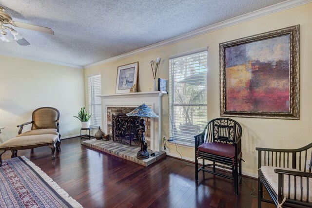 sitting room with a brick fireplace, a textured ceiling, ornamental molding, and a healthy amount of sunlight