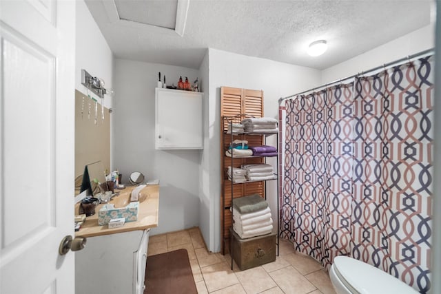 bathroom with tile patterned floors, vanity, toilet, and a textured ceiling