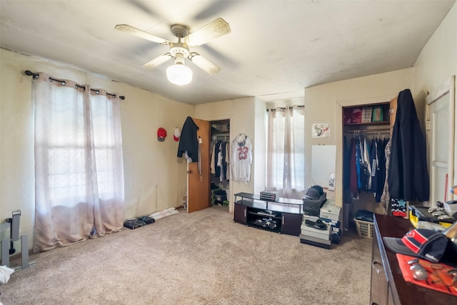 bedroom with ceiling fan, light colored carpet, and multiple windows