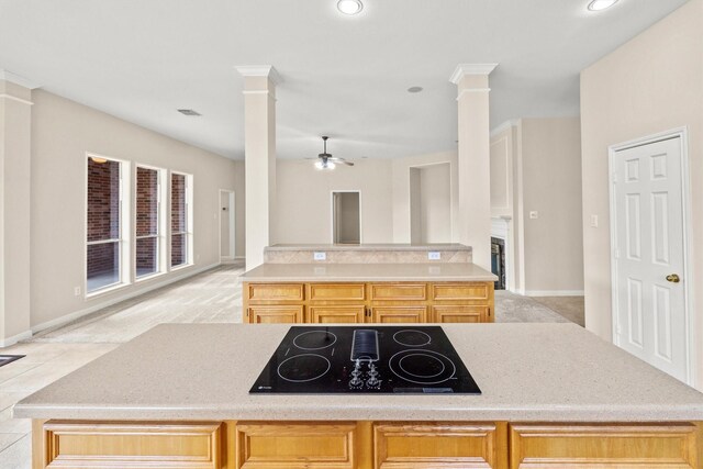 kitchen with a center island, black electric cooktop, ornate columns, and ceiling fan