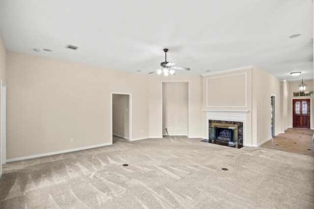 unfurnished living room with ceiling fan, light carpet, and a high end fireplace