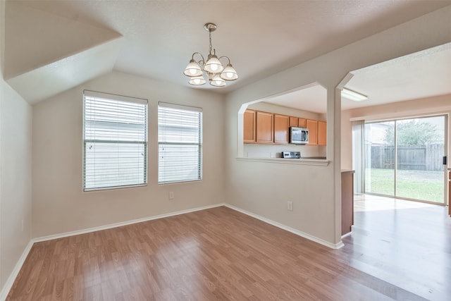 unfurnished dining area featuring an inviting chandelier, light wood-type flooring, and vaulted ceiling