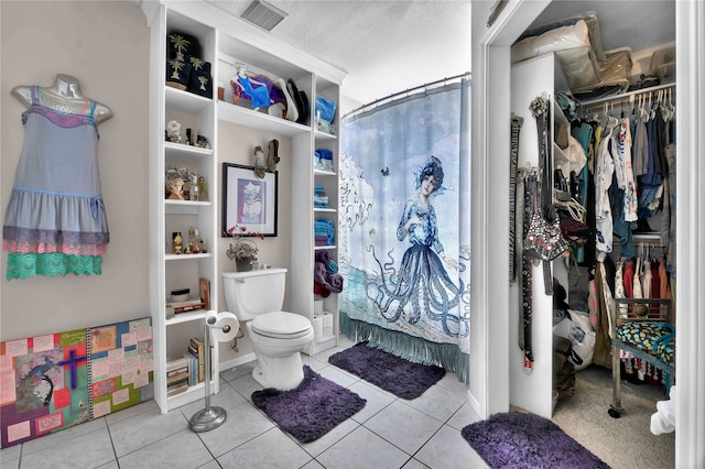 bathroom featuring toilet, a textured ceiling, tile patterned flooring, and a shower with shower curtain