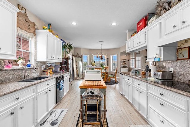 kitchen featuring light wood-type flooring, sink, light stone countertops, and white cabinets