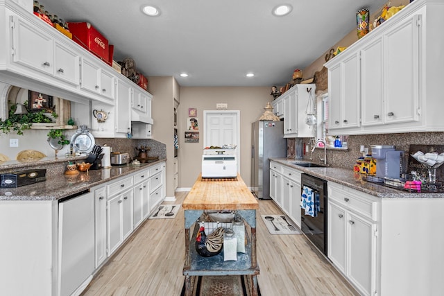 kitchen with dark stone countertops, white cabinetry, sink, and dishwasher