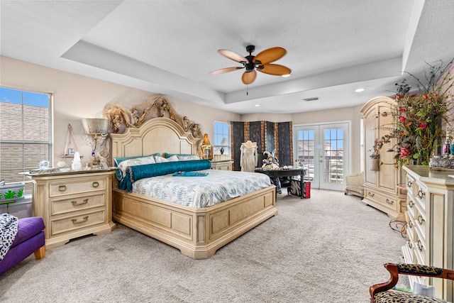 bedroom featuring ceiling fan, light colored carpet, a tray ceiling, and access to outside