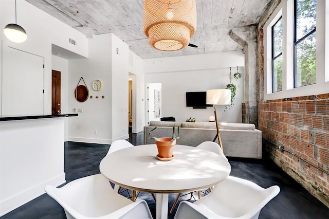 dining area featuring wood-type flooring and brick wall