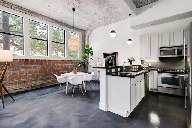 kitchen featuring white cabinets, appliances with stainless steel finishes, plenty of natural light, and hanging light fixtures