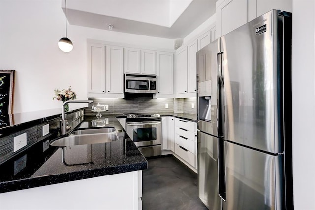 kitchen with tasteful backsplash, appliances with stainless steel finishes, white cabinetry, pendant lighting, and a sink