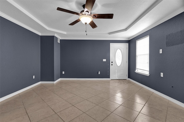 interior space with ceiling fan, a textured ceiling, a tray ceiling, and ornamental molding