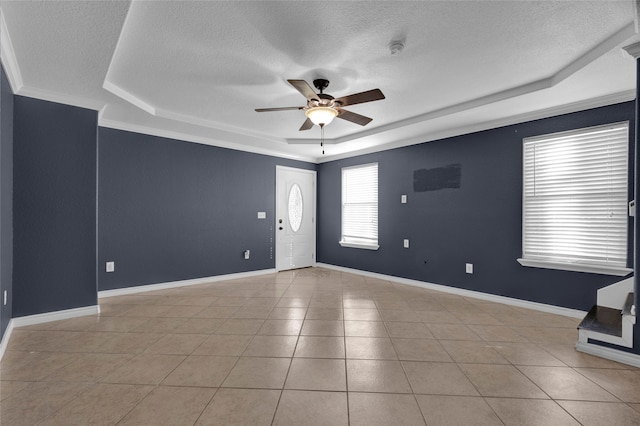 tiled spare room featuring a textured ceiling, crown molding, and a raised ceiling