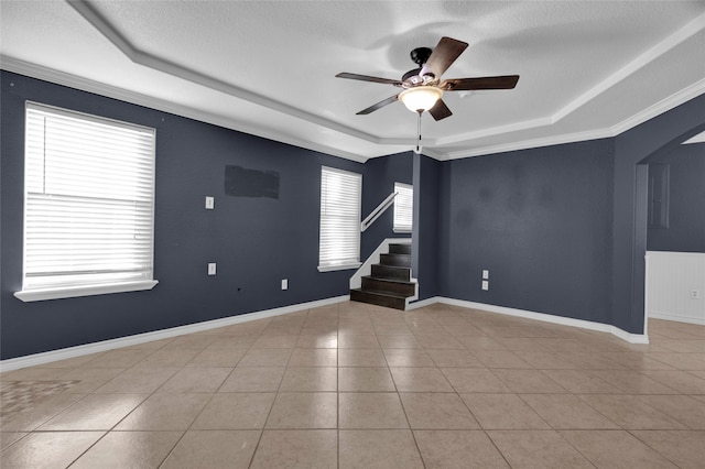 tiled spare room featuring a tray ceiling, a textured ceiling, ceiling fan, and crown molding