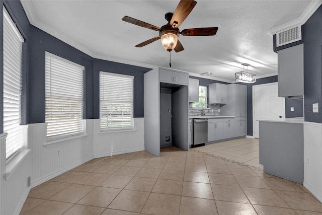 kitchen featuring stainless steel dishwasher, plenty of natural light, light tile patterned floors, and crown molding