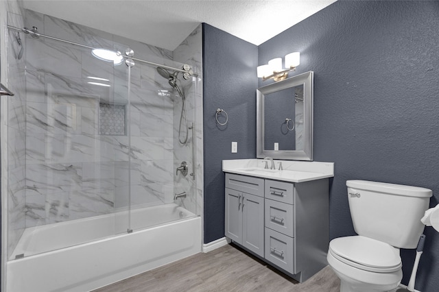 full bathroom featuring hardwood / wood-style flooring, tiled shower / bath, a textured ceiling, vanity, and toilet