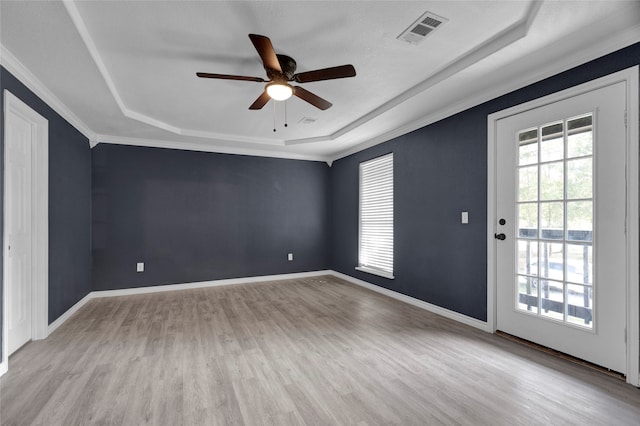 empty room with ceiling fan, ornamental molding, light hardwood / wood-style flooring, and a tray ceiling