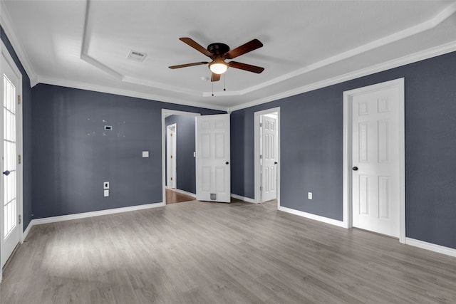 unfurnished bedroom featuring crown molding, a raised ceiling, hardwood / wood-style flooring, and ceiling fan