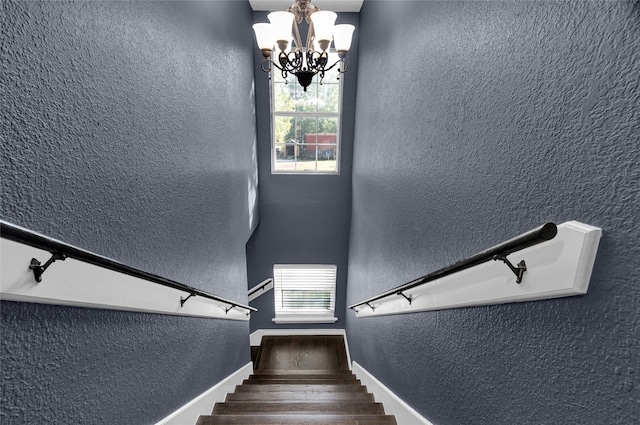 staircase with a healthy amount of sunlight and an inviting chandelier