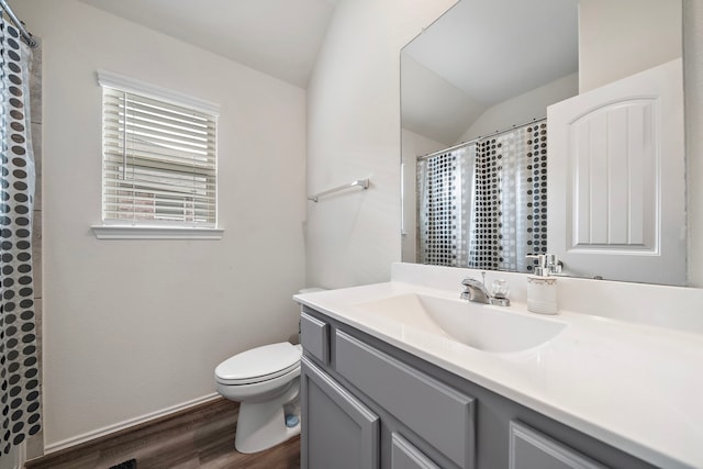 bathroom with toilet, vanity, lofted ceiling, and hardwood / wood-style flooring