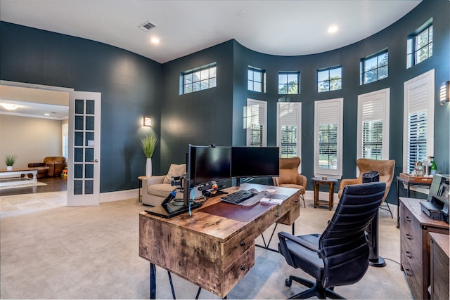 office space with french doors, a towering ceiling, and light colored carpet