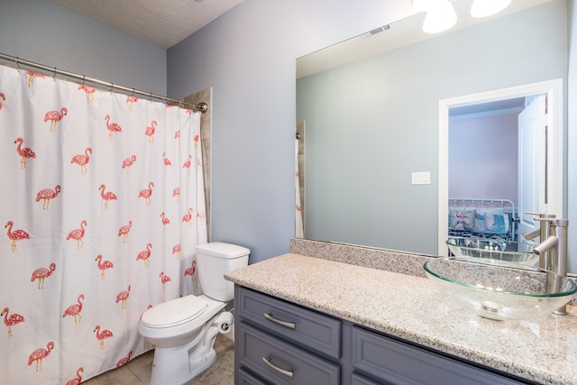 bathroom with tile patterned floors, vanity, a textured ceiling, and toilet