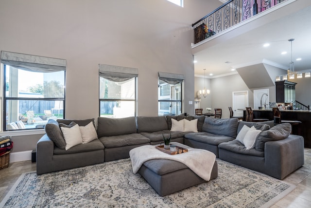 living room with a chandelier, a towering ceiling, and crown molding