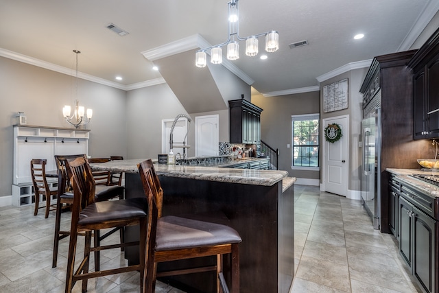 kitchen with a notable chandelier, decorative light fixtures, light stone countertops, ornamental molding, and dark brown cabinets