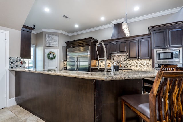 kitchen featuring built in appliances, light stone counters, dark brown cabinetry, and crown molding