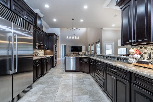 kitchen featuring backsplash, dark stone counters, crown molding, ceiling fan, and appliances with stainless steel finishes