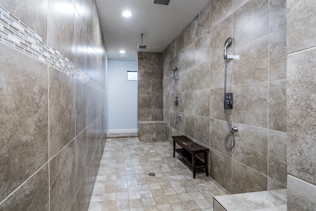 bathroom with a tile shower and a textured ceiling