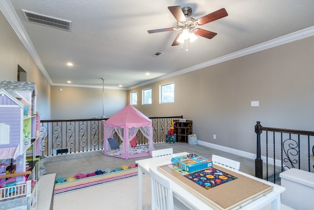 rec room with a textured ceiling, carpet floors, ceiling fan, and ornamental molding