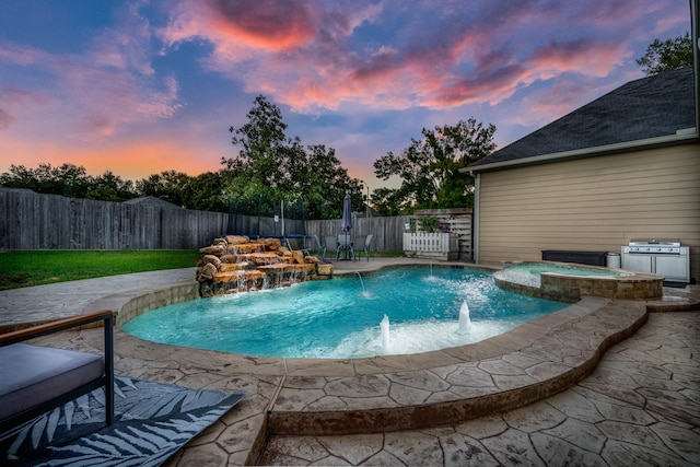 pool at dusk featuring an in ground hot tub, a patio, pool water feature, and area for grilling