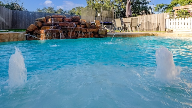 view of swimming pool featuring pool water feature and a trampoline