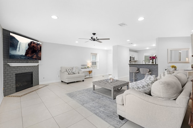 tiled living room featuring sink, ceiling fan, and a brick fireplace