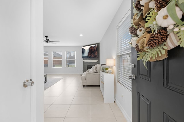 tiled foyer with a brick fireplace and ceiling fan