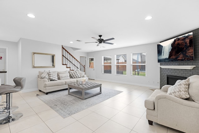 living room featuring a fireplace, light tile patterned flooring, and ceiling fan