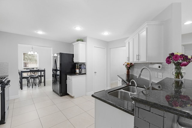 kitchen with white cabinets, black fridge, decorative backsplash, and gas stove