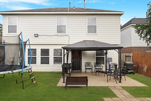 rear view of property featuring a trampoline, a patio area, a yard, and a gazebo