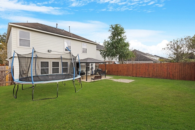 back of house featuring a lawn, a patio, a gazebo, and a trampoline