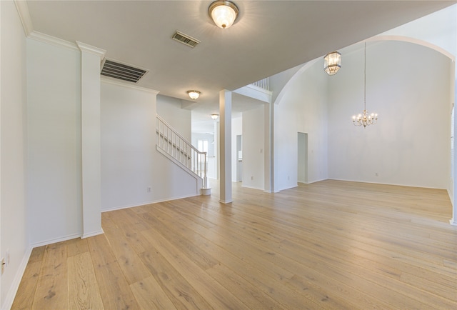 unfurnished room featuring light wood-type flooring, a chandelier, and crown molding