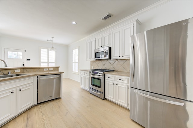 kitchen featuring white cabinets, hanging light fixtures, sink, and appliances with stainless steel finishes