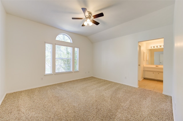 unfurnished bedroom with vaulted ceiling, light colored carpet, ceiling fan, and ensuite bathroom