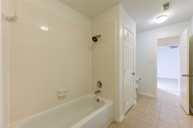 bathroom featuring toilet, tiled shower / bath combo, tile patterned floors, and ceiling fan