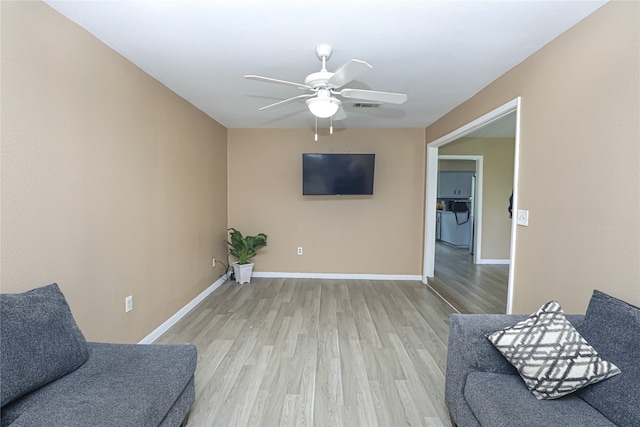 living area featuring light wood-type flooring, ceiling fan, and washer / dryer