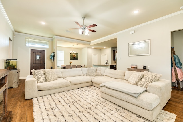 living room with wood-type flooring, ceiling fan with notable chandelier, and crown molding