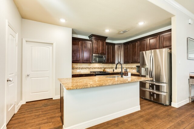 kitchen with stainless steel appliances, light stone countertops, sink, and dark wood-type flooring