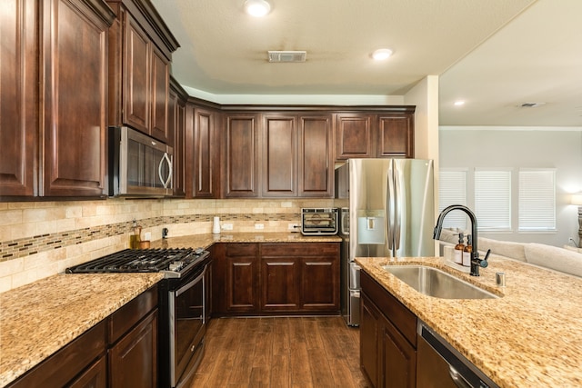 kitchen with stainless steel appliances, sink, dark hardwood / wood-style floors, dark brown cabinets, and decorative backsplash