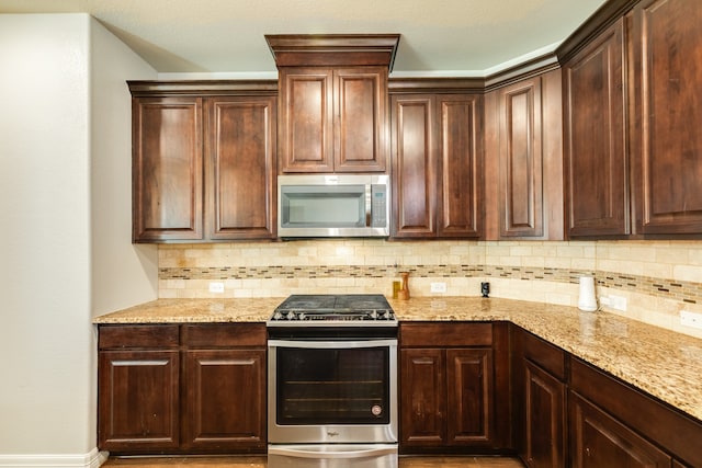 kitchen featuring appliances with stainless steel finishes, light stone counters, and tasteful backsplash